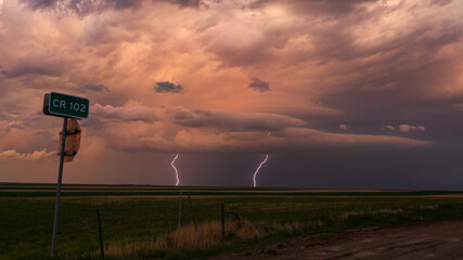 Multiple lightning bolts strike off in the distance underneath a dark and ominous sky as a thunderstorm passes through eastern Colorado