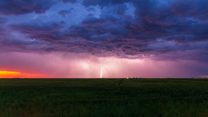 Fototapeta na wymiar Lightning bolt strikes at dusk on the Wyoming / Colorado border with dark storm clouds overhead