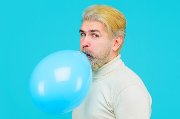 Happy birthday. Stylish bearded man blowing blue air balloon. Attractive male inflating balloon...