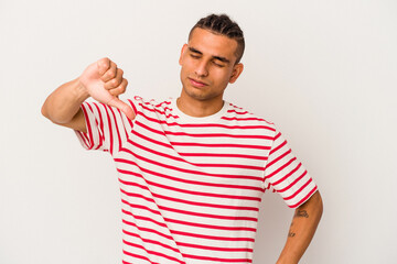 Young venezuelan man isolated on white background showing a dislike gesture, thumbs down....