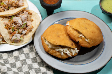 Carnitas tacos and chicharron gorditas on turquoise background. Mexican food