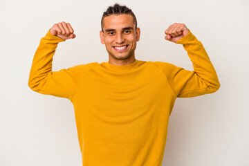 Young venezuelan man isolated on white background showing strength gesture with arms, symbol of feminine power