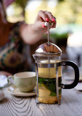 a woman pressing the plunger of a French press in the cafe 