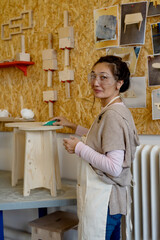 asian woman making stool  and working with sandpaper in  a woodworking shop