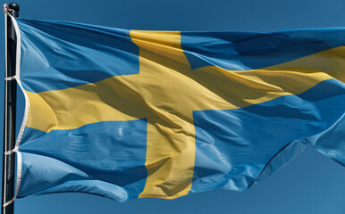 Blue flag of Sweden with a yellow cross fluttering in the wind. The concept of national symbols, international relations, Olympic and sports games. Close up shot