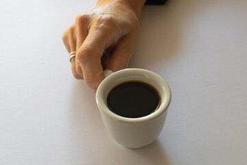 Hand holding a white coffee cup