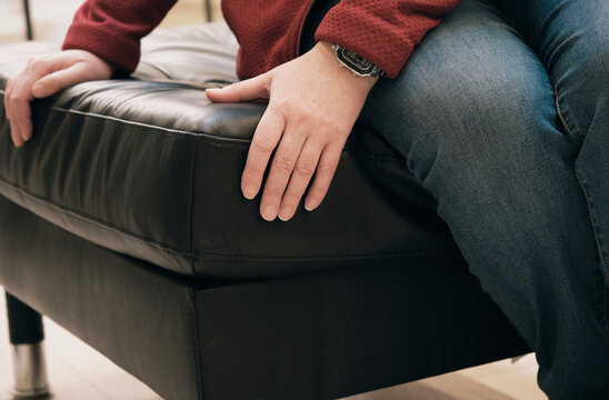 Caucasian woman in the store chooses for buy an ottoman made of brown leather. The concept of buying new home furniture, interior design and decor. Hands close up shot