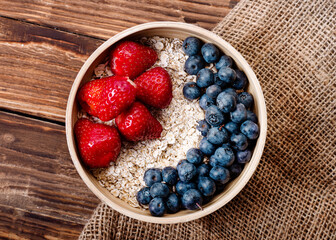 strawberries,  blueberries  and oatmeal in the bowl on wooden background