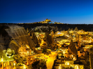 Goreme, Cappadocia, Turkey. View of the evening city from the mountain. Bright evening city and clear sky. Landscape in the summertime. Vacation and tourism.