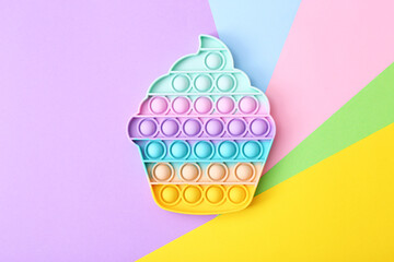 Trendy toy antistress, pop it on a rainbow background, fidget toy, top view - obrazy, fototapety, plakaty