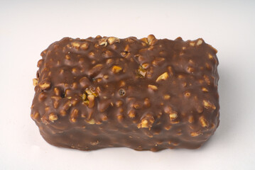 Sweet bar with nuts and doused with milk chocolate closeup.
