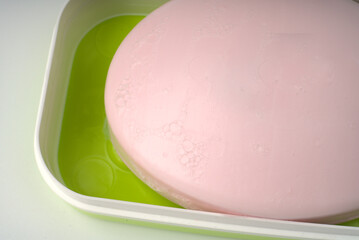Pink hand and face soap in a soap dish on a white background.