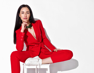 Young insolent brunette woman in red official pantsuit, jacket with deep neckline on naked body and...