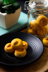 Asian peanut cookies on plate and glass jar on wooden background	
