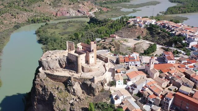 Picturesque autumn landscape with small Spanish town of Cofrentes located in mountainous area of Valencia province overlooking ancient fortified castle 