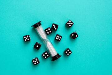 Black dice and sand timer on teal background.