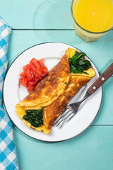Egg omelette with spinach and tomate on turquoise background. French food