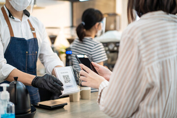Asian customer use phone Scan QR code to pay for drink in restaurant.