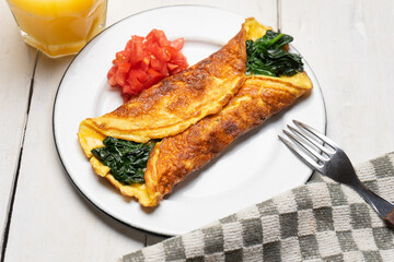 Egg omelette with spinach and tomate on white background. French food