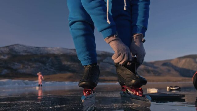 The Child Train On Ice Speed Skating. Athlete Puts On Skates. The Girl Skates In The Winter In Sportswear, Sport Glasses. Children Speed Skating Short Long Track, Kid Sport. Outdoor Slow Motion.