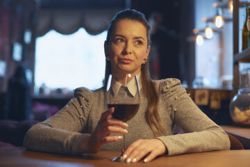Hand of a young beautiful woman holding a glass of wine indoors of a stylish wine restaurant