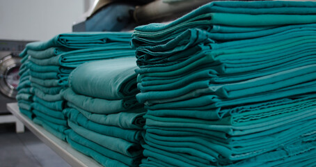 Stack of green folded surgical clothing in an industrial laundry.