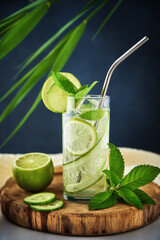Summer refreshment drink. Glass of water with kiwi, lime and mint on dark background. Homemade lemonade with ice