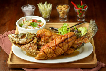 Close up Deep fried Snapper with fish sauce on vintage wooden, The perfect frying process, Set hot fire, then bring the snapper to fry to frame and topped with fish sauce.