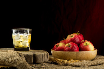 Apple juice in a champagne glass and apples in a wooden bowl on vintage background