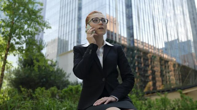 Young business woman with ginger red hair talking on mobile phone in down town.