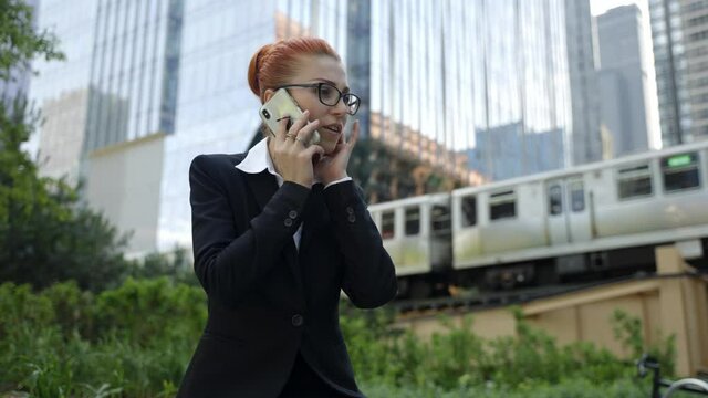 Young business woman with ginger red hair talking on mobile phone in down town.