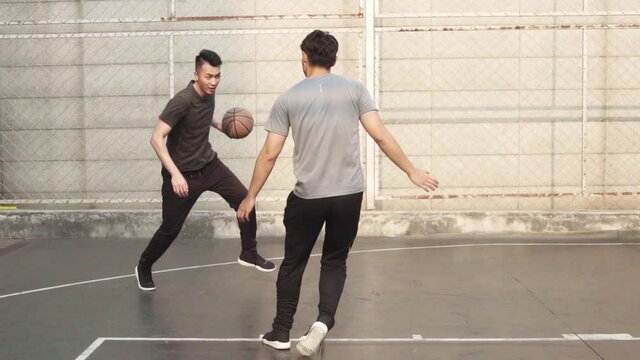 group of asian young adult men playing basketball for fun on outdoor court
