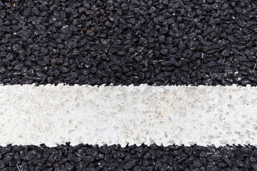 close up of a dark asphalt road divided by white paint, close up of white traffic lines on the dark asphalt road background