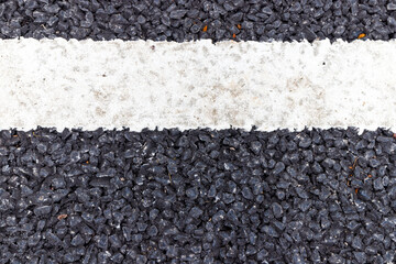 close up of a dark asphalt road divided by white paint, close up of white traffic lines on the dark asphalt road background