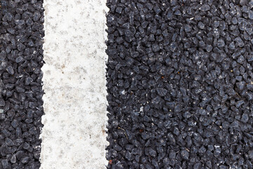 close up of a dark asphalt road divided by white paint, close up of white traffic lines on the dark asphalt road background