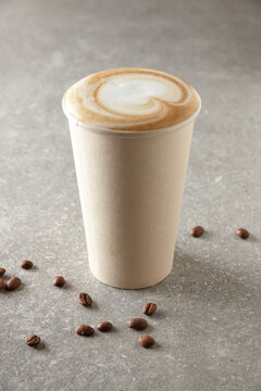 Paper coffee cup and coffee beans on table