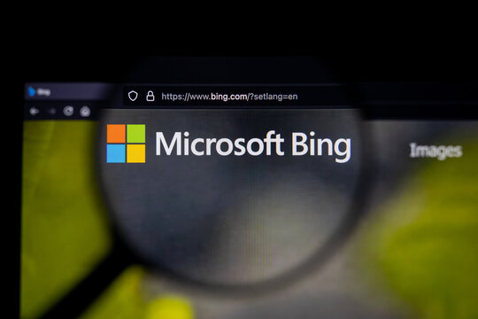 Bing search engine  logo on a website, seen on a computer screen through a magnifying glass.