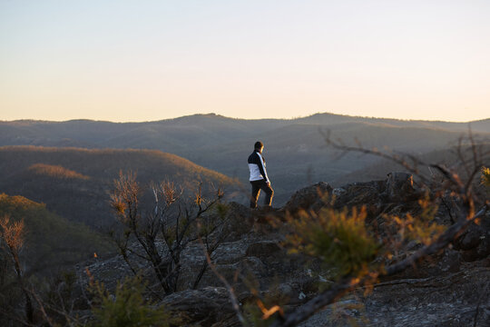 Man standing looking out over mountains on sunset