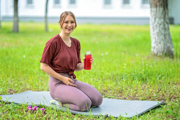 Beautiful smiling girl holds a bottle of fruit drink in hands,drinks between approaches in training