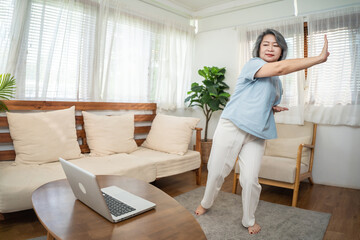 Asian senior eldery woman exercise, follow sport yoga video at home.