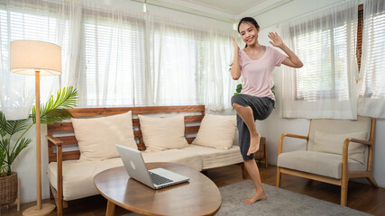 Asian girl doing aerobics exercise by learning from video tutorial.	