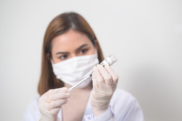 Young female doctor holding a syringe with covid-19 vaccine bottle for injection, covid-19 vaccination and health care concept