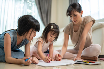 Little siblings girl enjoy draw and color picture with mother on floor