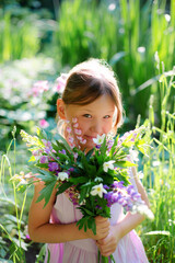 Six year old girl with bouquet of flowers in the forest.