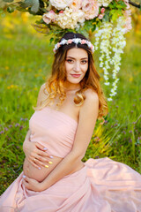 Fototapeta na wymiar Smiling pregnant woman resting in the park. Pretty pregnant woman posing outdoors. Happy pregnant woman relaxing outside in the park outdoor. Maternity. Expectant mother waiting and preparing for baby