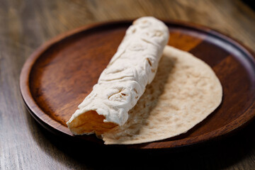 rolled flatbread pita on a round wooden cutting board. bakery. flat bread