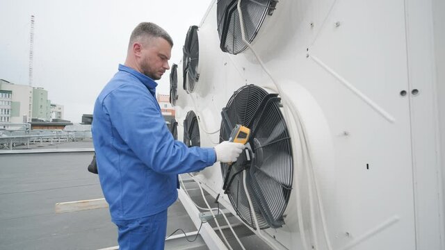 Technician uses a thermal imaging infrared thermometer to check the condensing unit heat exchanger