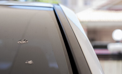 The stains of bird droppings on the windshield make the car look dirty and need to be cleaned.