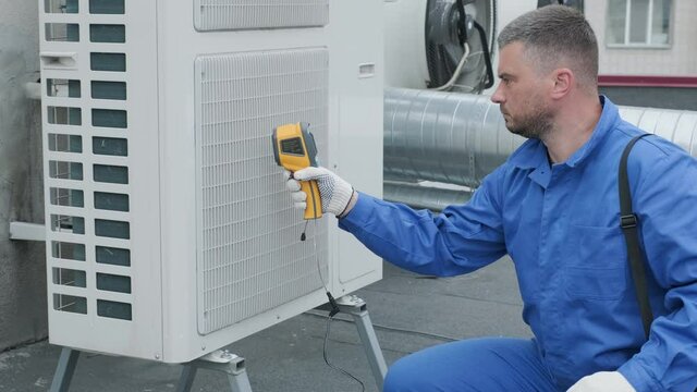 Technician uses a thermal imaging infrared thermometer to check the condensing unit heat exchanger