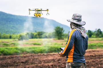 Technician farmer use control agriculture drone fly to sprayed fertilizer on farmland